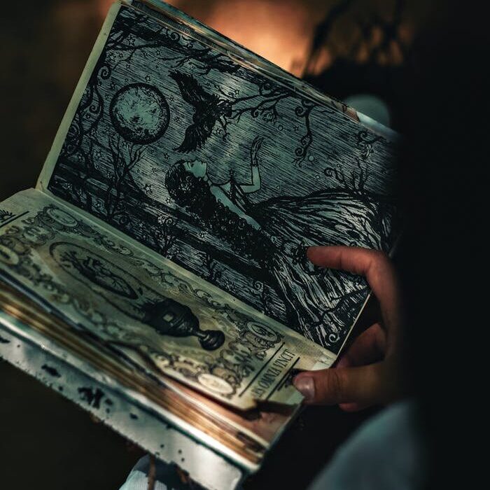 A hand holding a book with mystical illustrations, captured in artistic lighting.